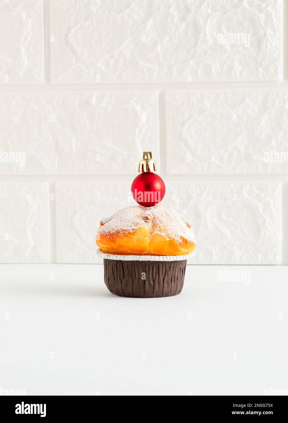 Concetto di vacanza minimal fatto di cupcake con rosso Natale abbauble sul tavolo. Concetto di cibo per il nuovo anno. Sfondo muro di mattoni. Foto Stock