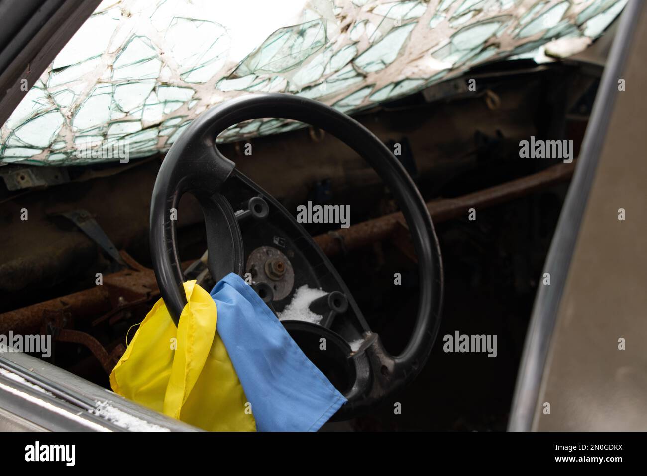 Un veicolo militare sparato e la bandiera dell'Ucraina sul volante si trova in Ucraina per strada, un veicolo militare bruciato 2023 Foto Stock