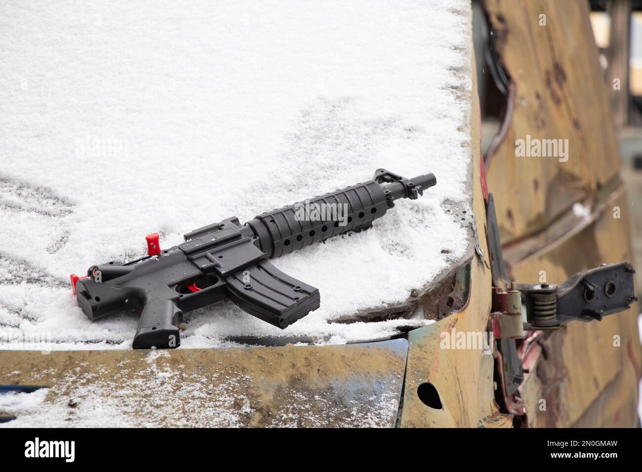 Una pistola di plastica per bambini si trova su un veicolo militare naufragato per strada in Ucraina in inverno, la guerra in Ucraina Foto Stock