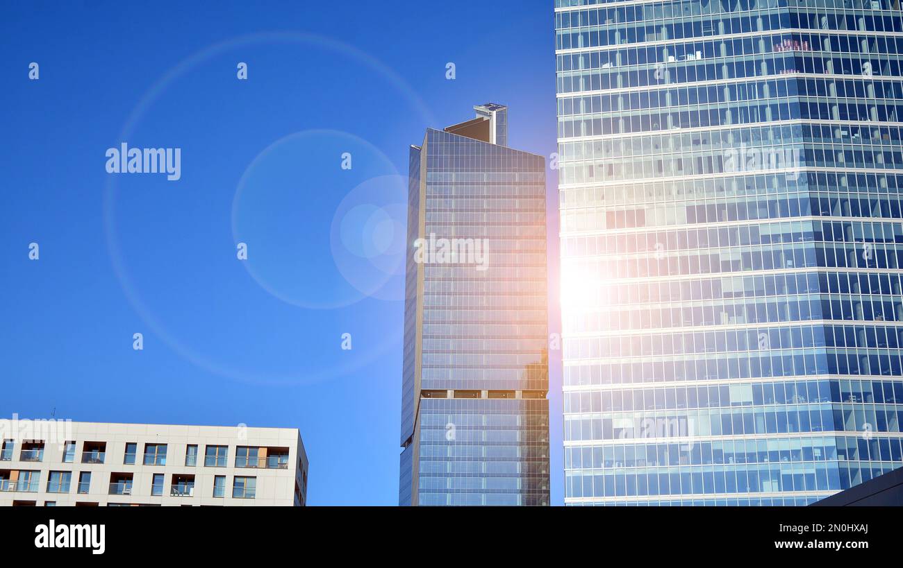 Parete a tendina blu realizzata in vetro tondo e costruzioni in acciaio sotto il cielo blu. Un frammento di un edificio. Facciate in vetro in una giornata di sole Foto Stock