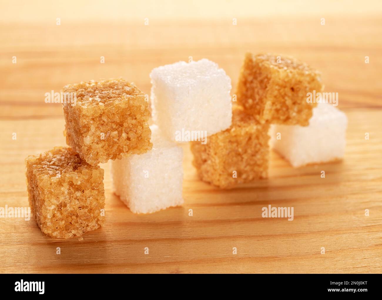 Diversi cubetti di zucchero di canna e bianco, da vicino, su un tavolo di legno. Foto Stock