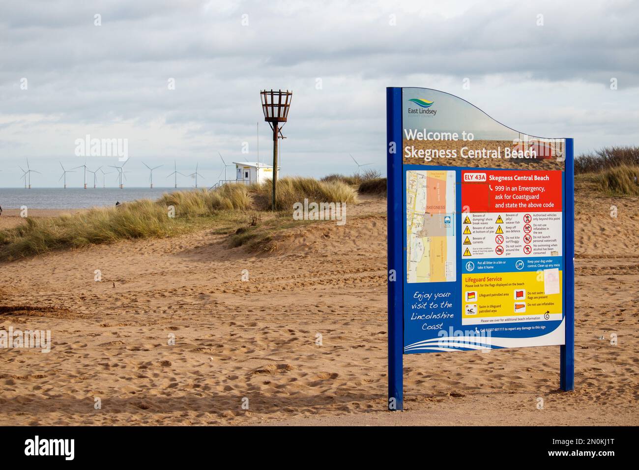 La vista verso il mare attraverso la spiaggia centrale a Skegness all'inizio di febbraio. In mare si può vedere la grande fattoria di tubiere a vento. Al centro si trova il faro che si illumina per occasioni speciali. Foto Stock