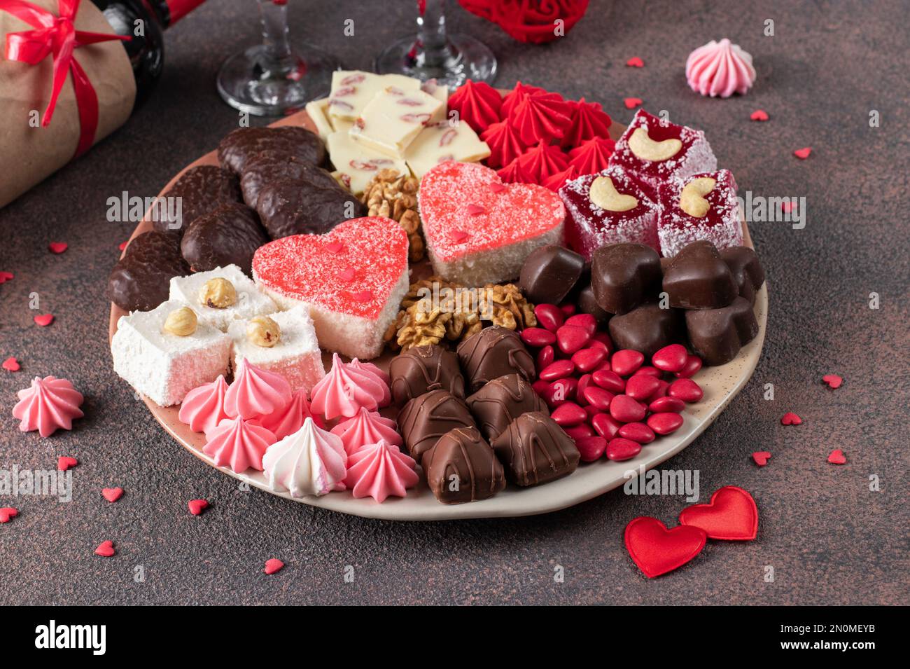 Dolce piatto romantico con torte di gelatina, cioccolato, noci, meringa e delizia turca il giorno di San Valentino su sfondo marrone, Closeup Foto Stock