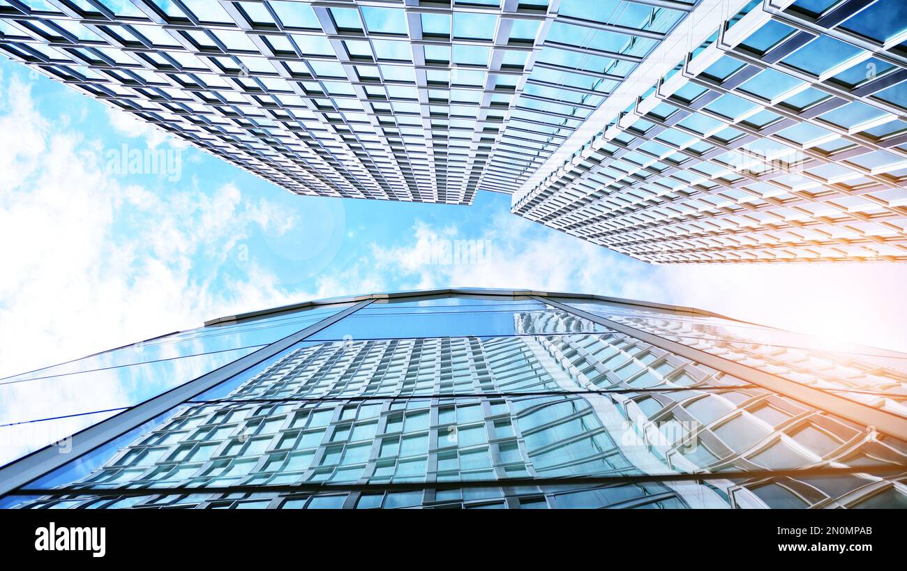 Moderno edificio di uffici con facciata in vetro su uno sfondo cielo chiaro. Primo piano astratto della facciata rivestita in vetro di un edificio moderno Foto Stock