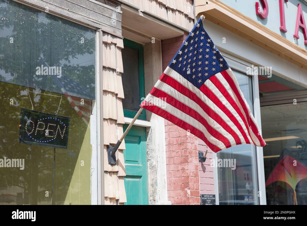 Bandiera americana di fronte a un edificio, una vetrina sulla strada principale. Foto Stock