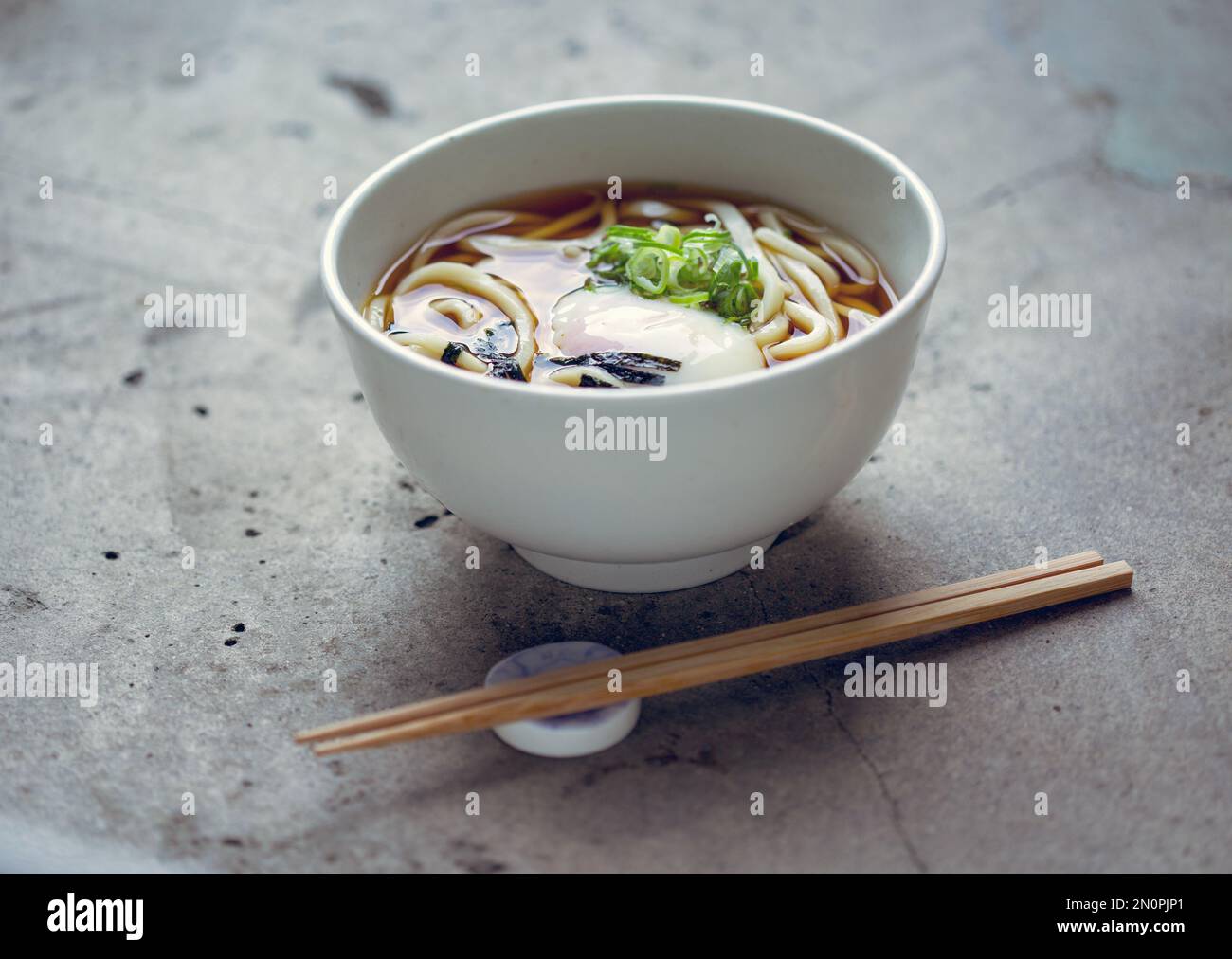 Una ciotola di tagliatelle, verdure e brodo e una serie di bastoncini. Foto Stock