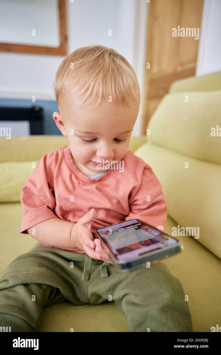 Bambino che guarda lo smartphone in casa Foto Stock