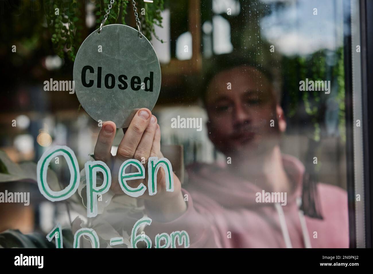 Uomo che mette il segno chiuso nella finestra del negozio Foto Stock