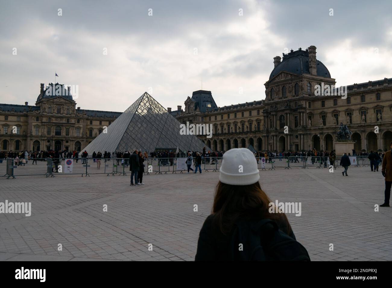 Pirâmide du Louvre. Le Louvre è il museo più visitato al mondo, la pirâmide di vetro. Visita di Parigi nel mese di gennaio con il freddo nei giorni di nuvoloso. Turisti. Foto Stock