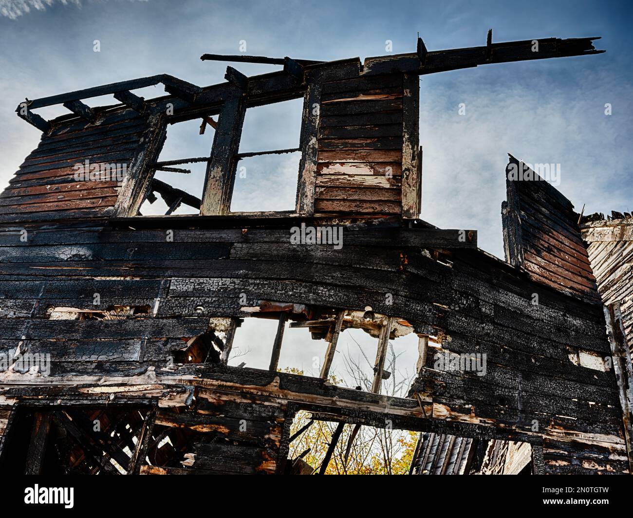 Alcune travi bruciate e una facciata in legno sono tutti che rimangono di una casa distrutta da arson. Foto Stock