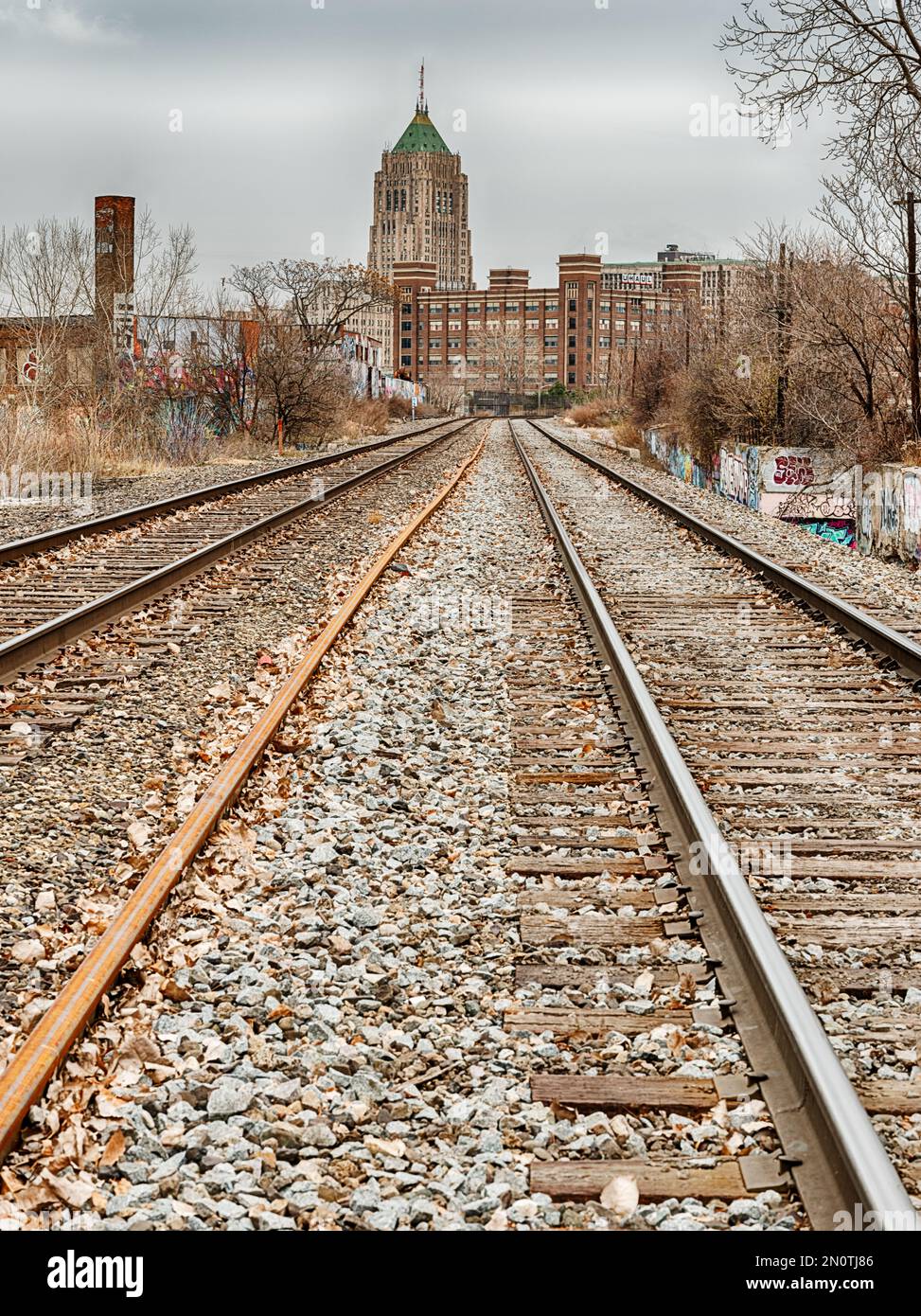 I binari ferroviari nell'area di Lincoln Park di Detroit conducono ad un edificio di uffici nell'area di Midtown. Foto Stock