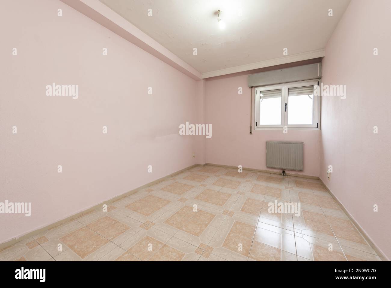 Camera completamente vuota con pareti dipinte di rosa e vecchi pavimenti in gres in due tonalità di colore Foto Stock