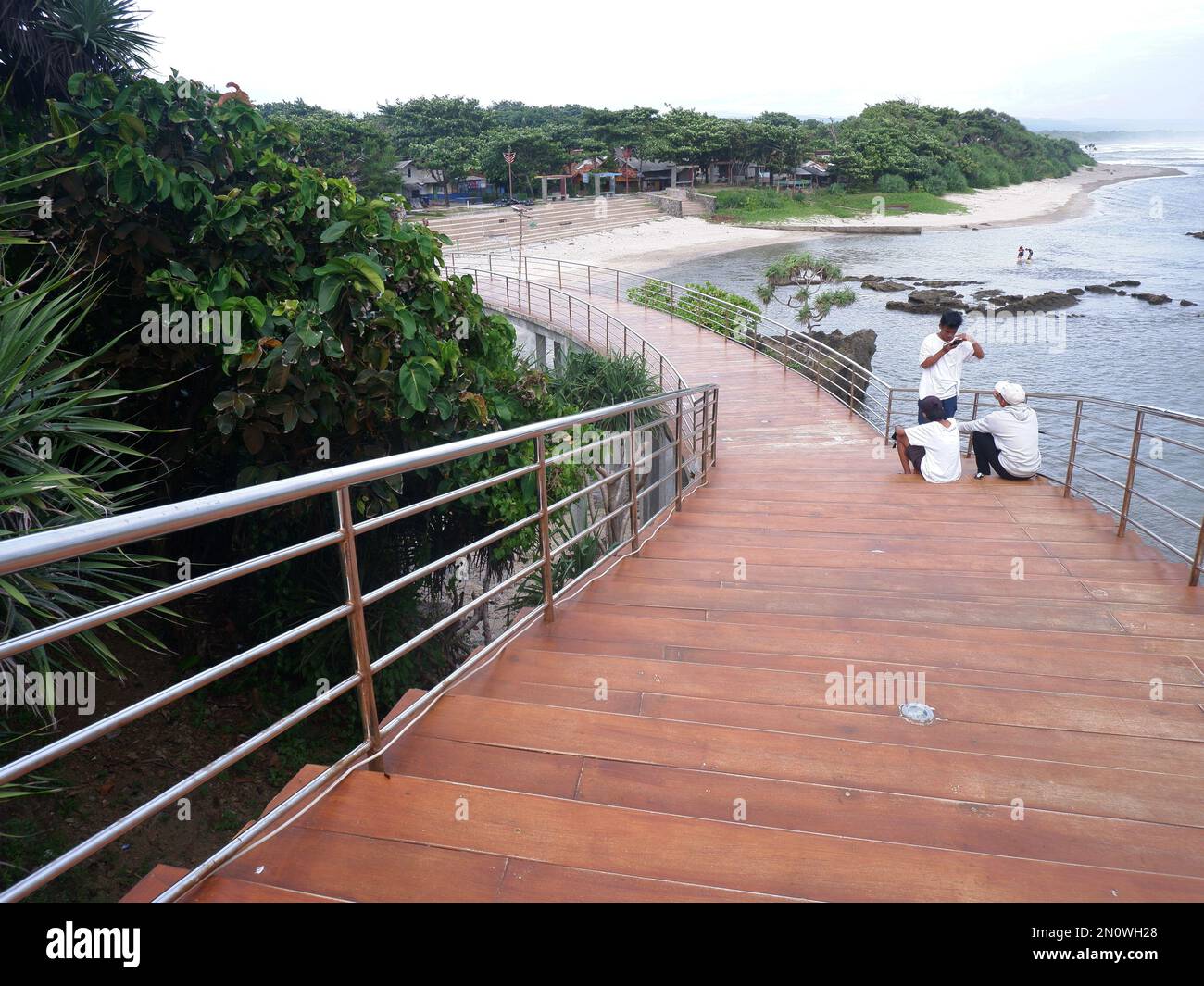 Garut, Indonesia- dicembre 12,2022: Persone sedute o ricreative sulla strada o sul ponte o sulle scale di legno sulla spiaggia, Vista della spiaggia brid Foto Stock