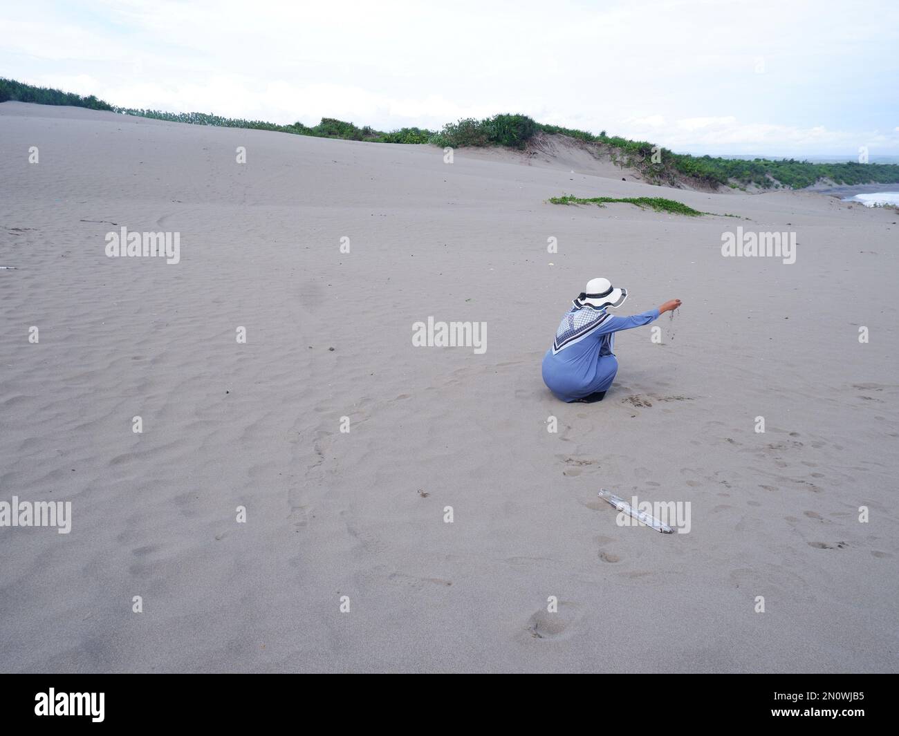 Dietro la donna nel cappello sulla spiaggia tropicale che era seduta sulla sabbia della spiaggia e fissava l'oceano, formò l'amore dalla mano. backgrou Foto Stock