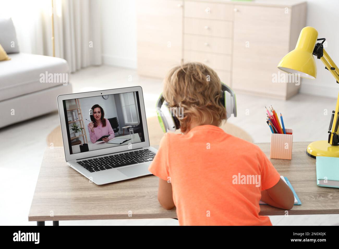 Bambino che studia con l'insegnante tramite videoconferenza a casa. Apprendimento a distanza durante la pandemia COVID-19 Foto Stock