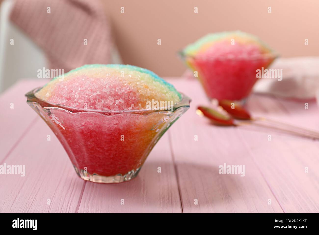 Ghiaccio da barba arcobaleno in ciotole di vetro da dessert su tavolo di legno rosa all'interno Foto Stock