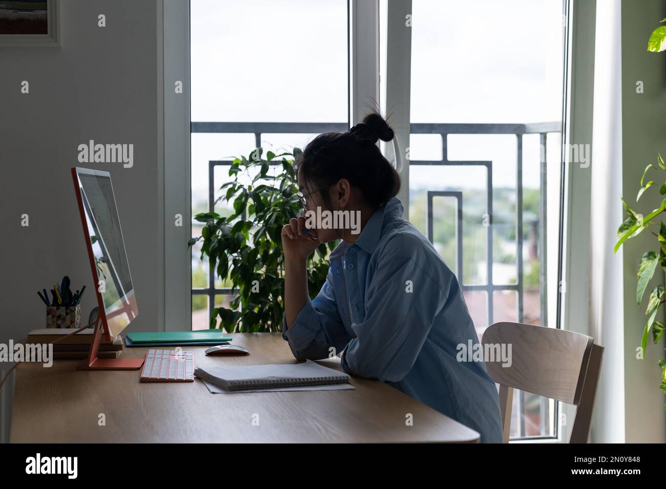 Un imprenditore asiatico di donna messo a fuoco autosufficiente siede alla scrivania con il computer in ufficio domestico Foto Stock