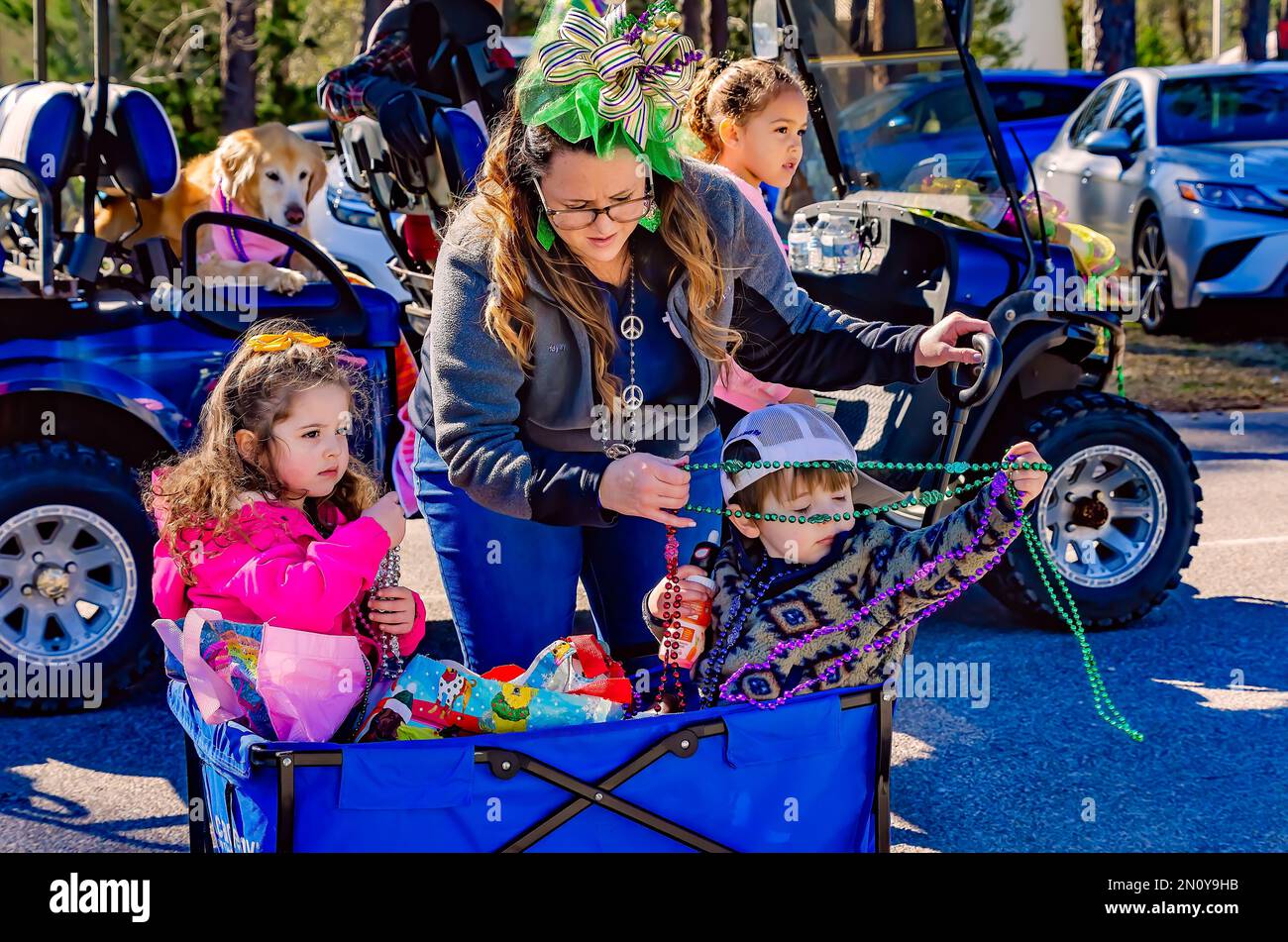 Una donna aiuta un bambino a sgombrare le perline di Mardi Gras durante la parata Mystic Krewe of Salty Paws Mardi Gras, 4 febbraio 2023, a Dauphin Island, Alabama. Foto Stock