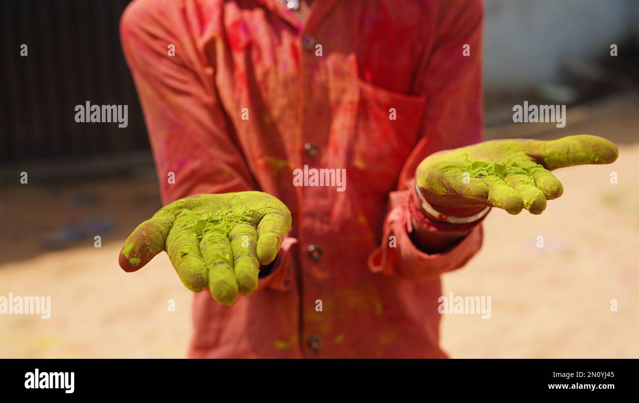 bambina indiana che mostra palma colorata e celebra holi con spruzzi di colore Foto Stock