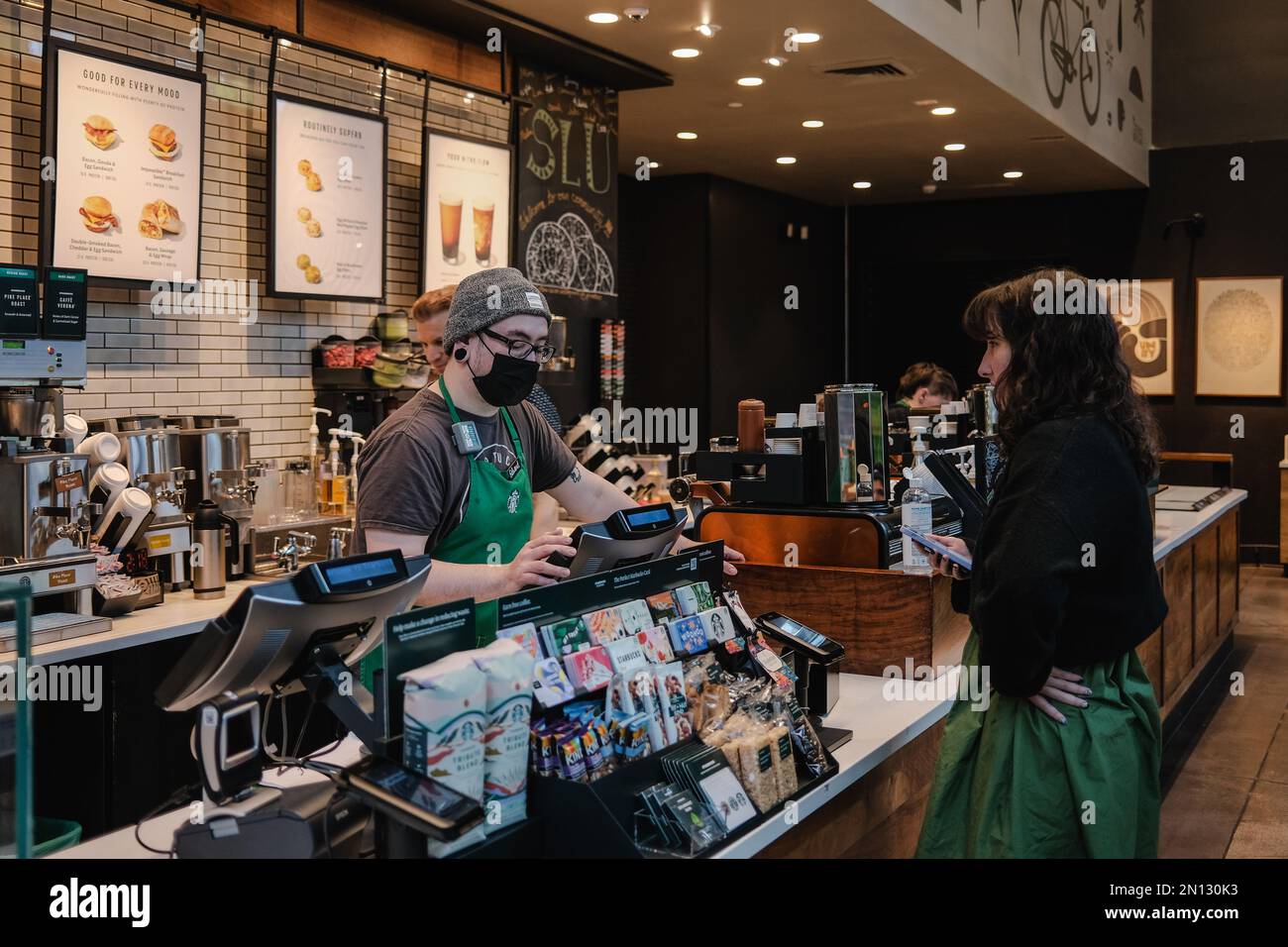 Un cliente acquista un drink all'interno del negozio Starbucks Seattle Downtown. Starbucks ha annunciato la chiusura del suo negozio situato a Broadway e Denny a Capitol Hill, Seattle, a causa di "incidenti di sicurezza". La posizione, che è stato il primo negozio Starbucks a unionizzare a Seattle, ha suscitato polemiche tra i dipendenti che affermano che la chiusura è il risultato di una tattica di Unione-busting. Workers United, il sindacato dei dipendenti, sostiene che la chiusura è prevista per l'anniversario della formazione del sindacato lo scorso anno, e il negozio Capitol Hill è il quarto luogo unico di Seattle a chiudere. Foto Stock