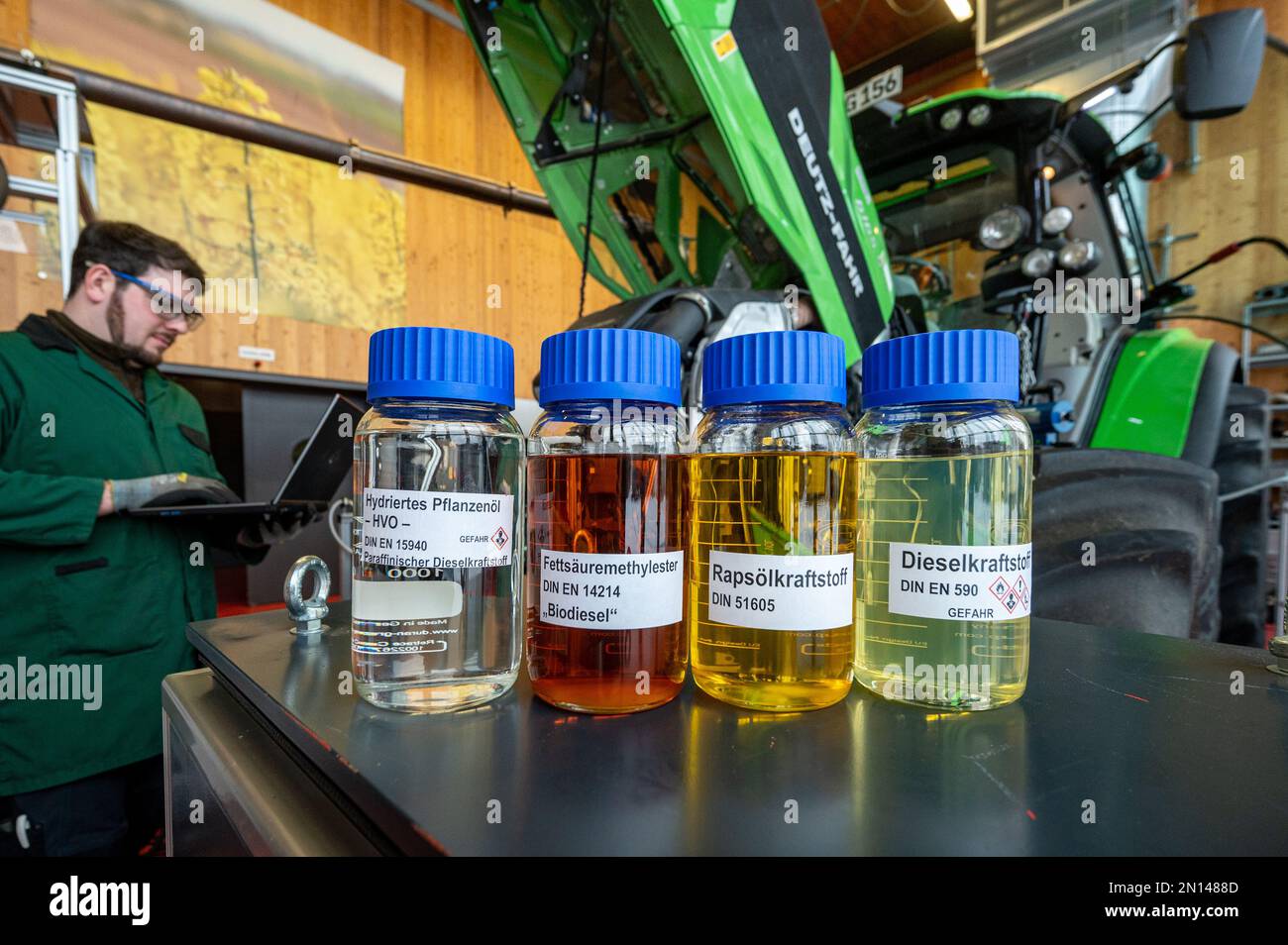 Straubing, Germania. 02nd Feb, 2023. Bottiglie campione di olio vegetale  (l-r), biodiesel, olio di colza e carburante diesel, si trovano di fronte a  un trattore in un laboratorio di prova presso il