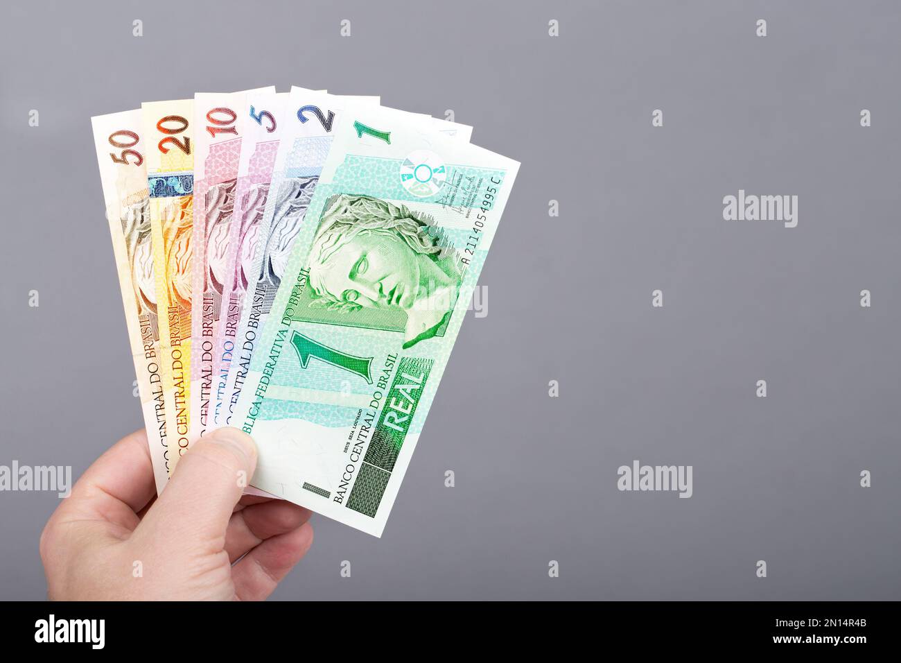Vecchio denaro brasiliano - Reais in mano su uno sfondo grigio Foto Stock