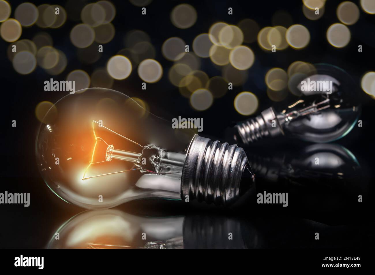 primo piano della lampadina al tungsteno con luce su sfondo scuro e luci sfocate Foto Stock