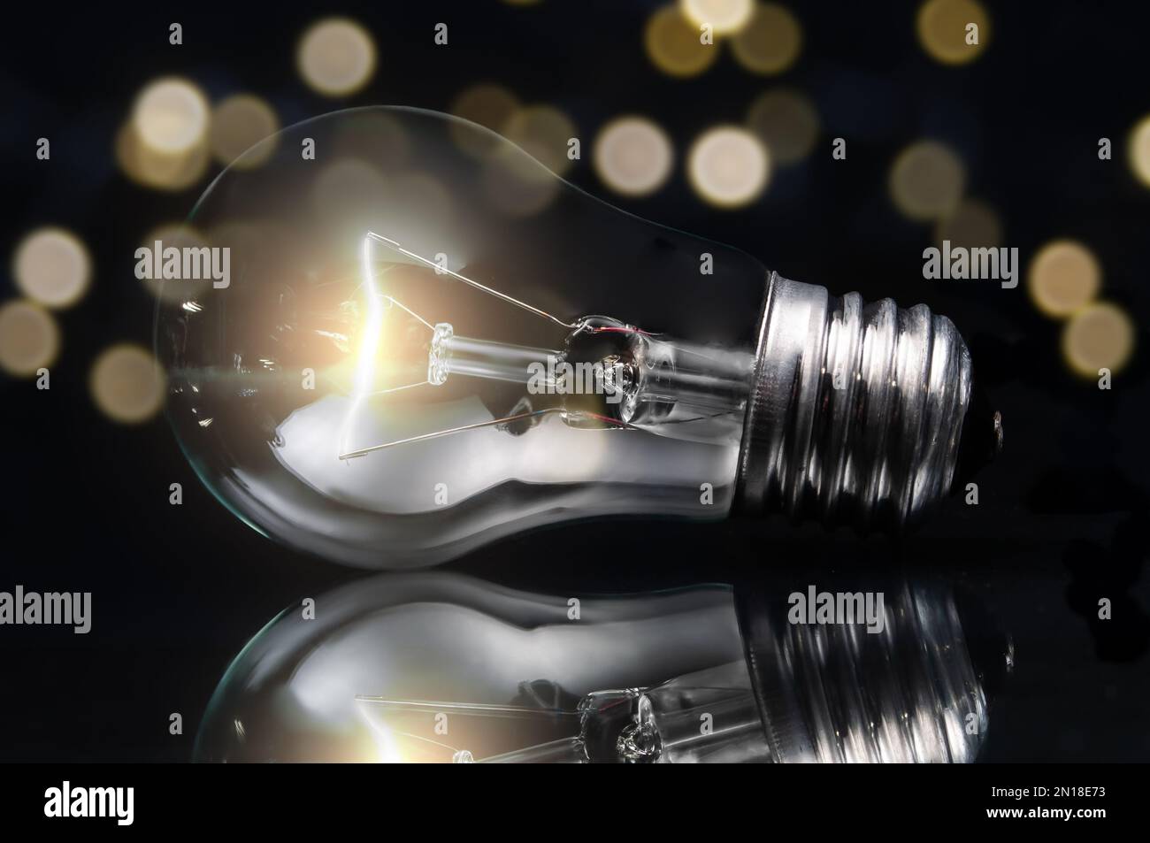 primo piano della lampadina al tungsteno con luce su sfondo scuro e luci sfocate Foto Stock