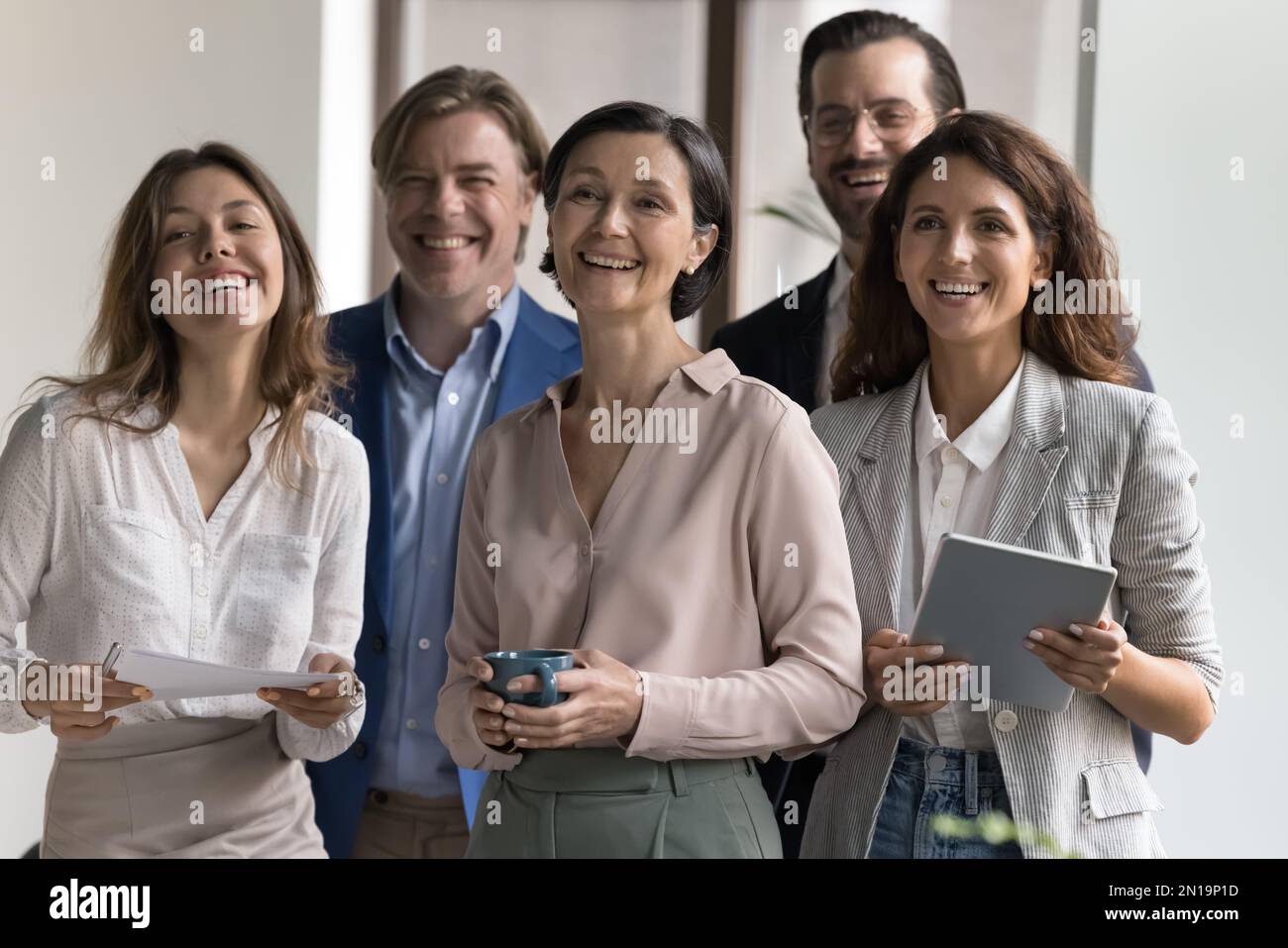 Felice gruppo di diversi dipendenti che si riuniscono in ufficio Foto Stock