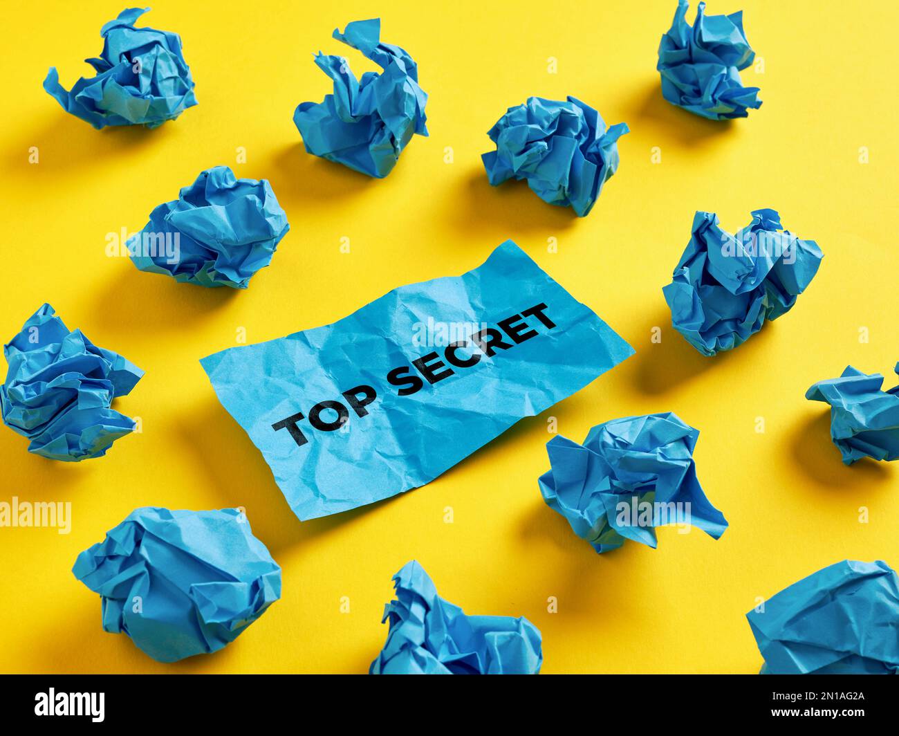 Cercare, rivelare o trovare le informazioni riservate più segrete. La parola top secret su pezzo di carta tra le palline di carta blu stropicciate. Foto Stock