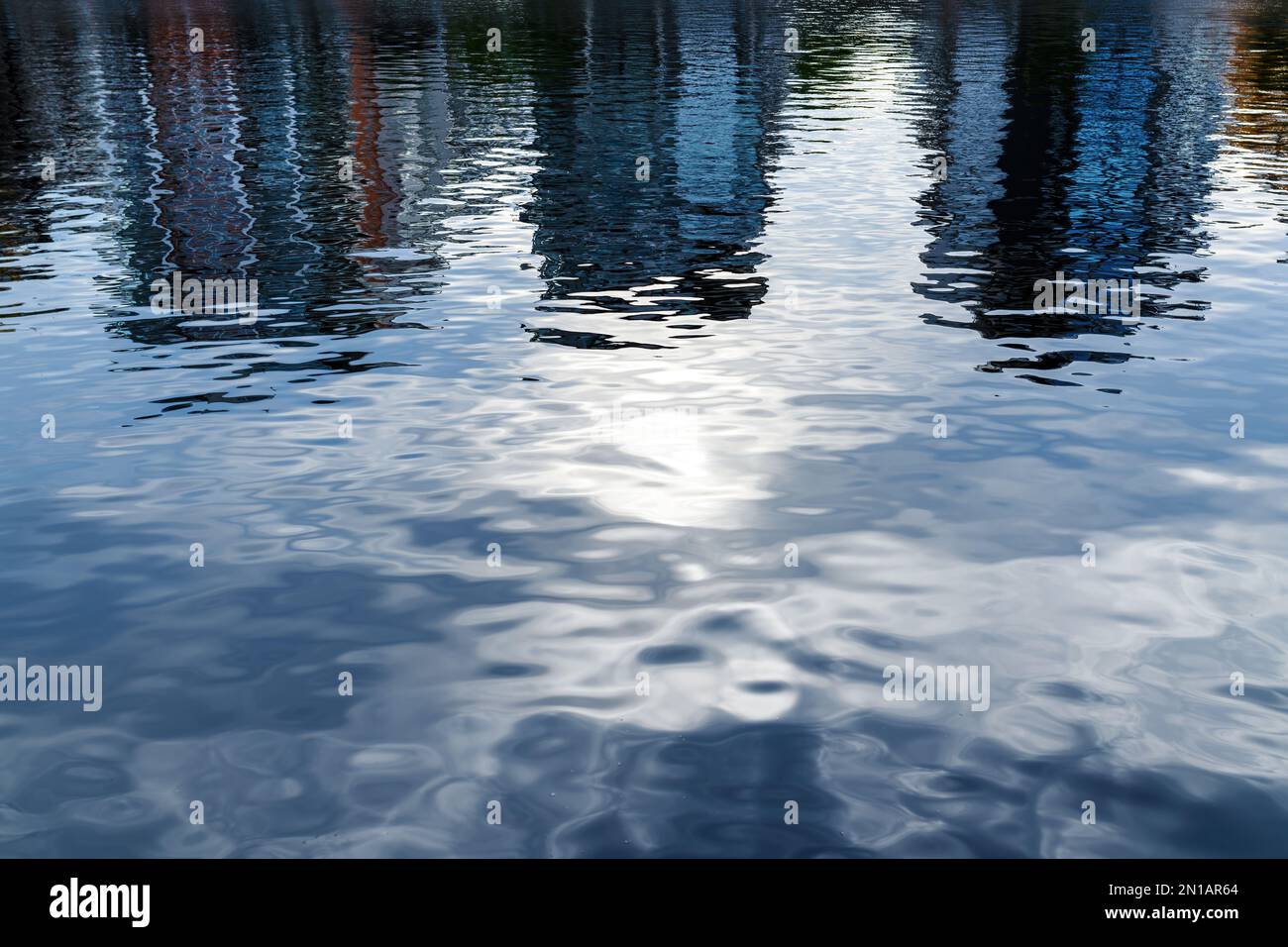 Riflessione degli edifici residenziali del distretto sulla superficie dell'acqua del fiume nelle giornate estive Foto Stock