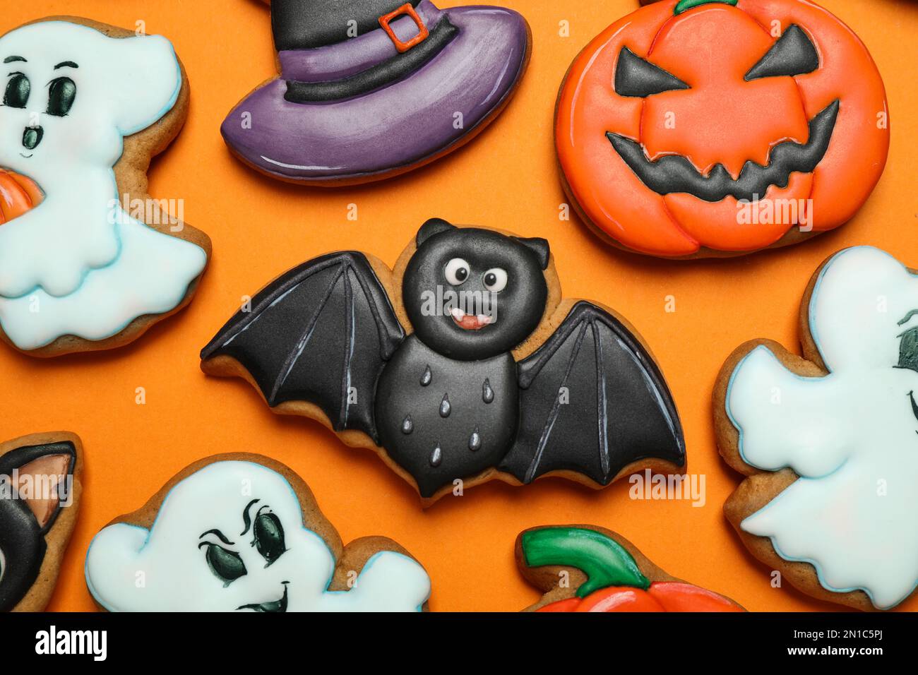 Biscotti di pan di zenzero decorati in modo diverso su fondo arancione, giacitura piatta. Festa di Halloween Foto Stock