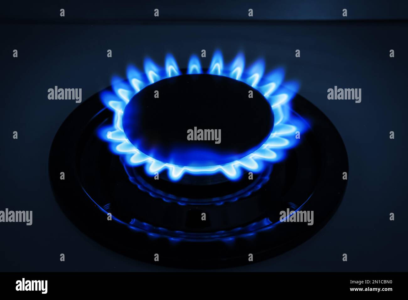 Bruciatore a gas di stufa moderna con fiamma blu che brucia di notte Foto Stock