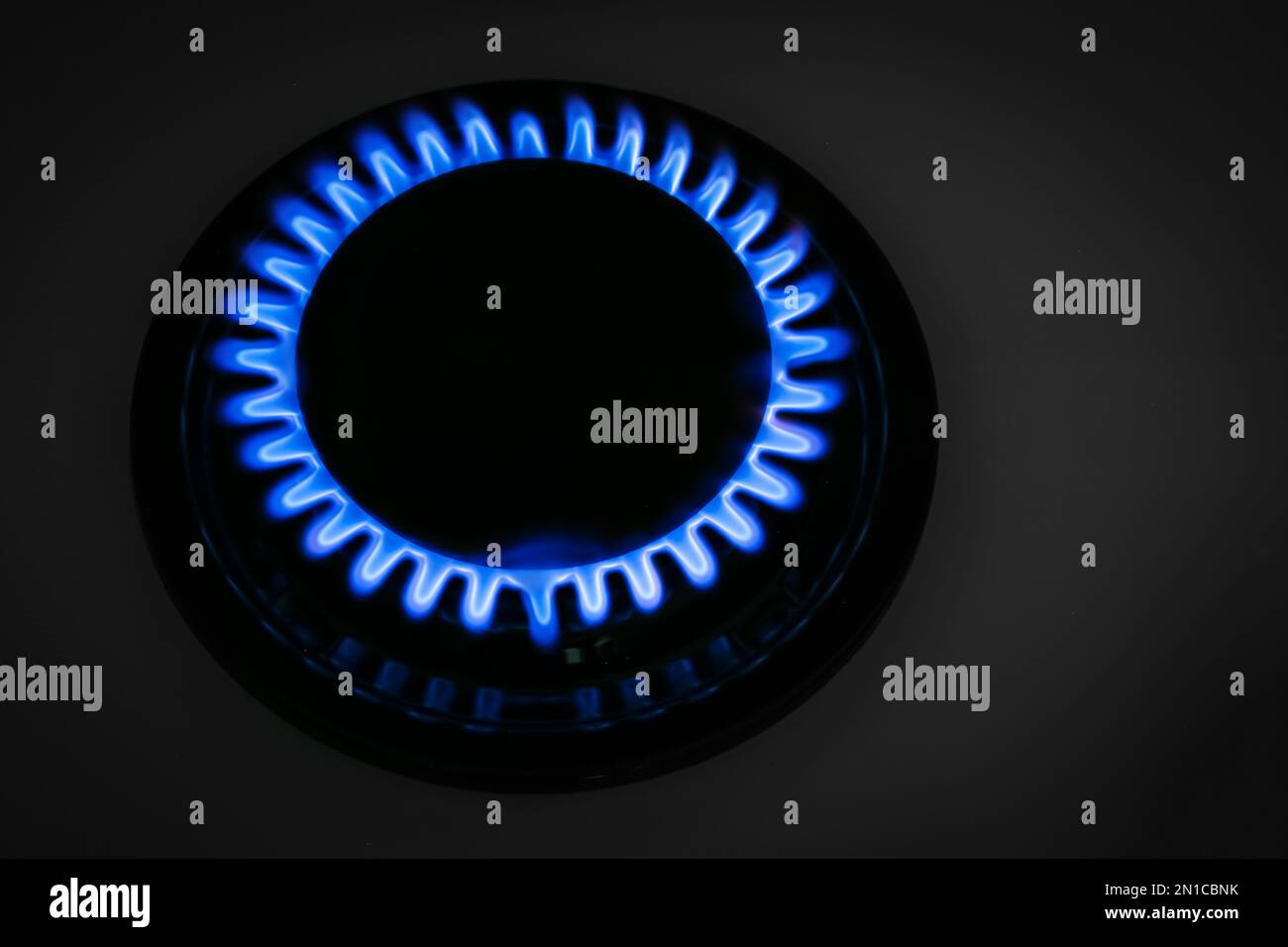 Bruciatore a gas di stufa moderna con fiamma blu che brucia di notte, primo piano Foto Stock