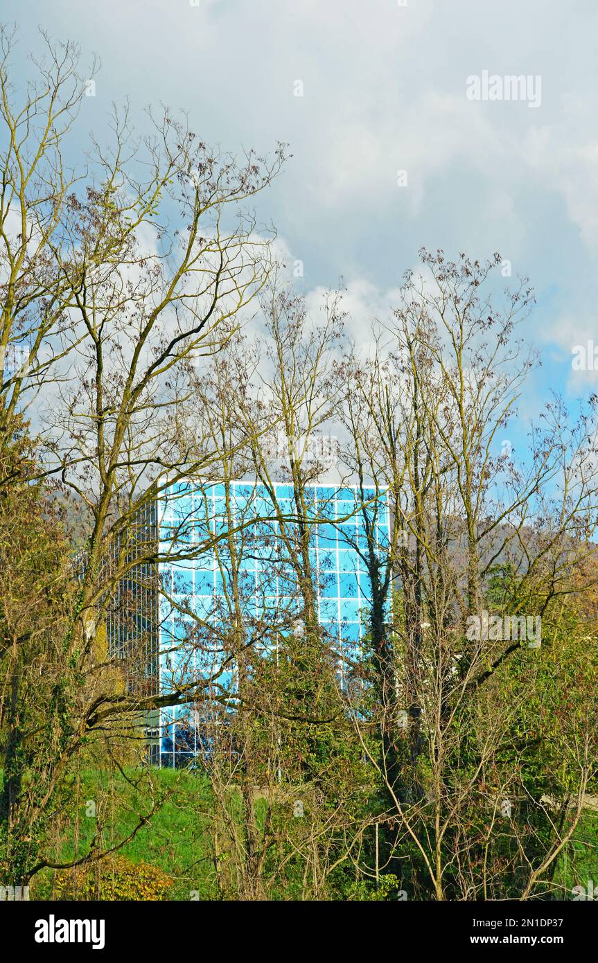 La facciata di un moderno edificio blu visibile attraverso alti alberi Foto Stock