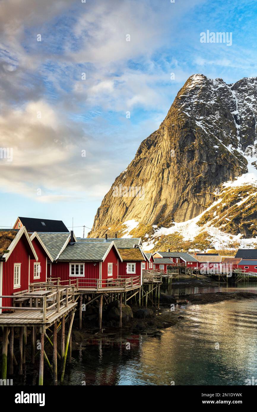 Colorate cabine di pescatori incorniciate da montagne maestose, Reine, Isole Lofoten, contea di Nordland, Norvegia, Scandinavia, Europa Foto Stock