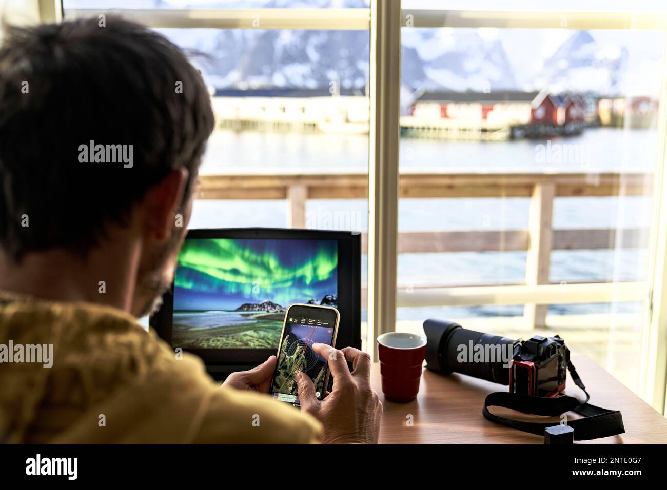 Fotografo che utilizza un computer portatile e uno smartphone per pianificare i viaggi fotografici, Isole Lofoten, Norvegia, Scandinavia, Europa Foto Stock