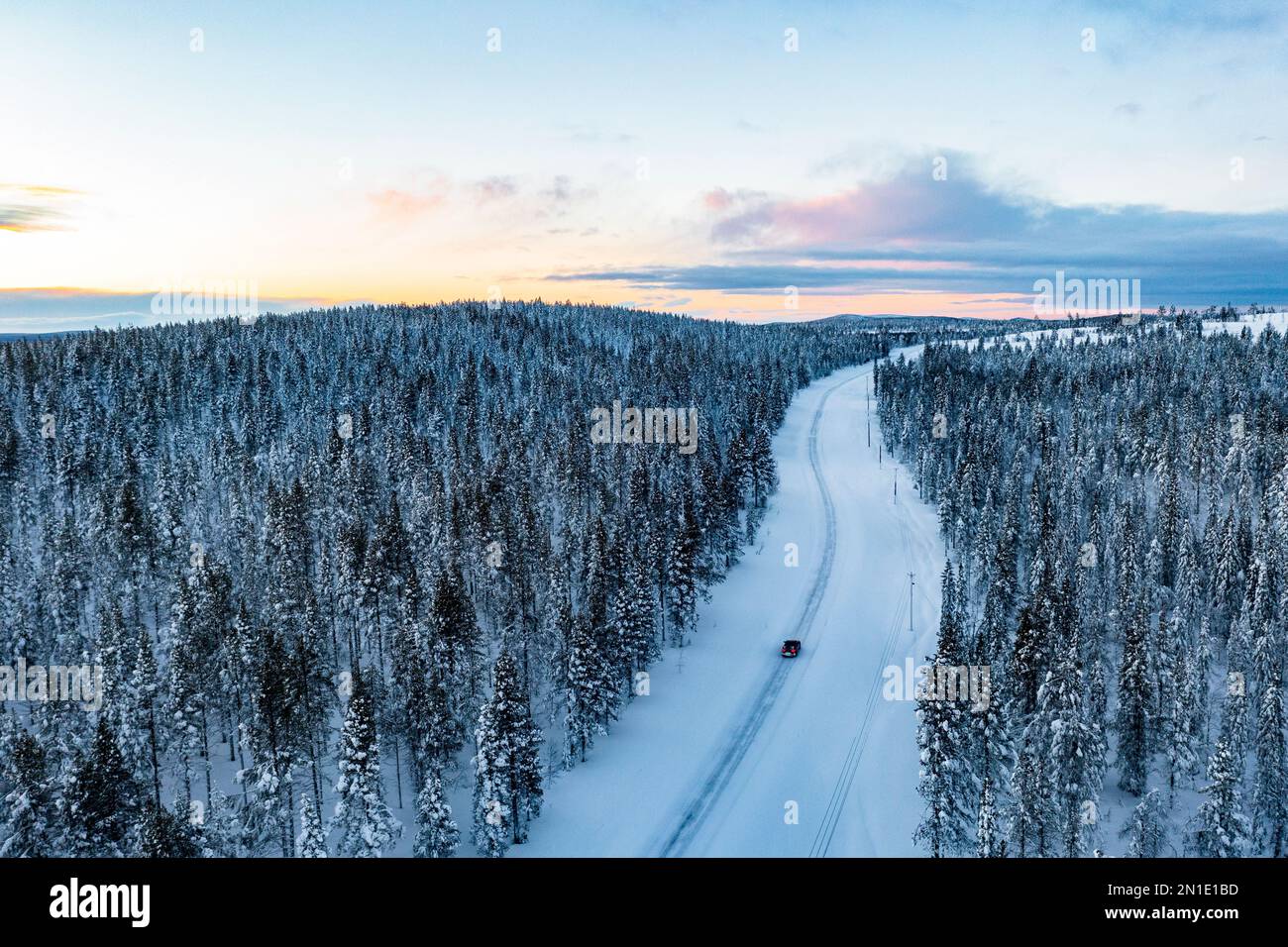 Auto che viaggia nella foresta innevata al tramonto, vista aerea, Gallivare, Norrbotten County, Lapponia, Svezia, Scandinavia, Europa Foto Stock