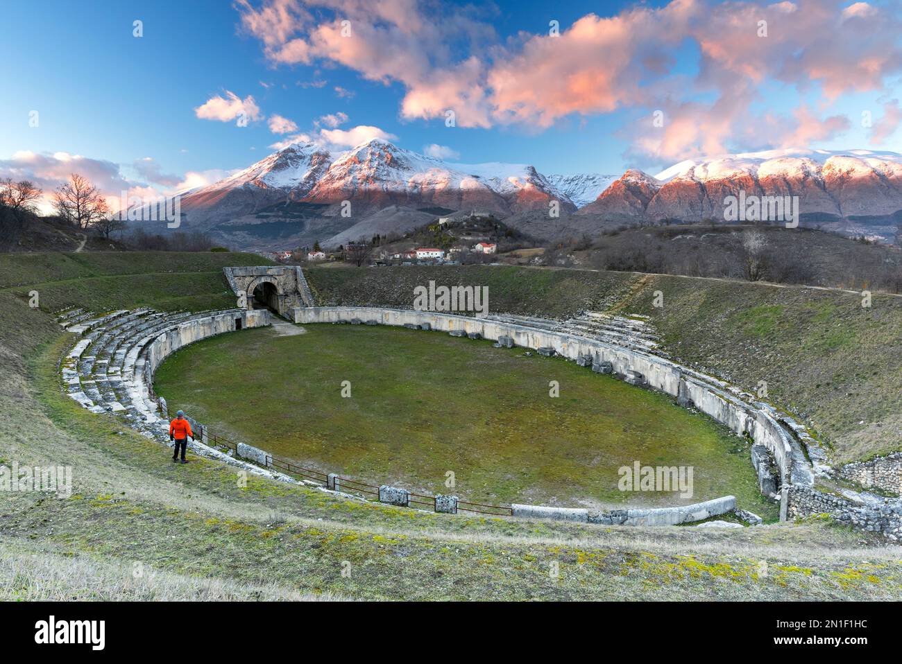 L'uomo gode della vista dell'antico anfiteatro e della vetta innevata al tramonto, Alba Fucens, l'Aquila, Appennino, Abruzzo, Italia, Europa Foto Stock