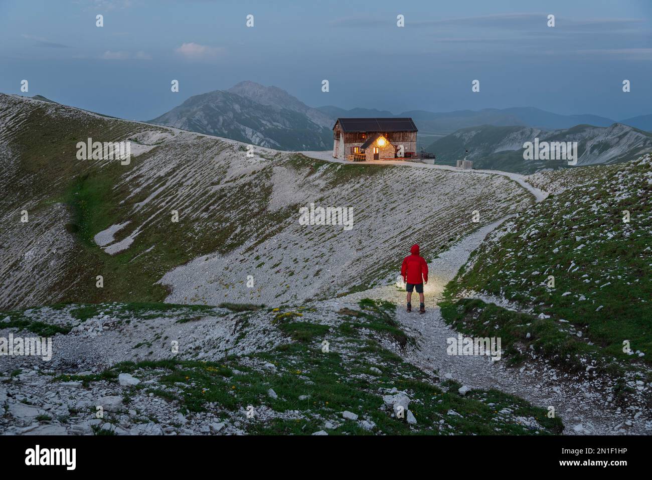 L'escursionista si trova sul sentiero del rifugio Duca degli Abruzzi al crepuscolo, campo Imperatore, Appennino, Abruzzo, Italia, Europa Foto Stock