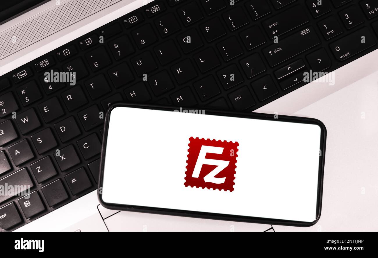 Software di protocollo di trasferimento file su schermo mobile con laptop sullo sfondo, sfondo editoriale filezilla Foto Stock