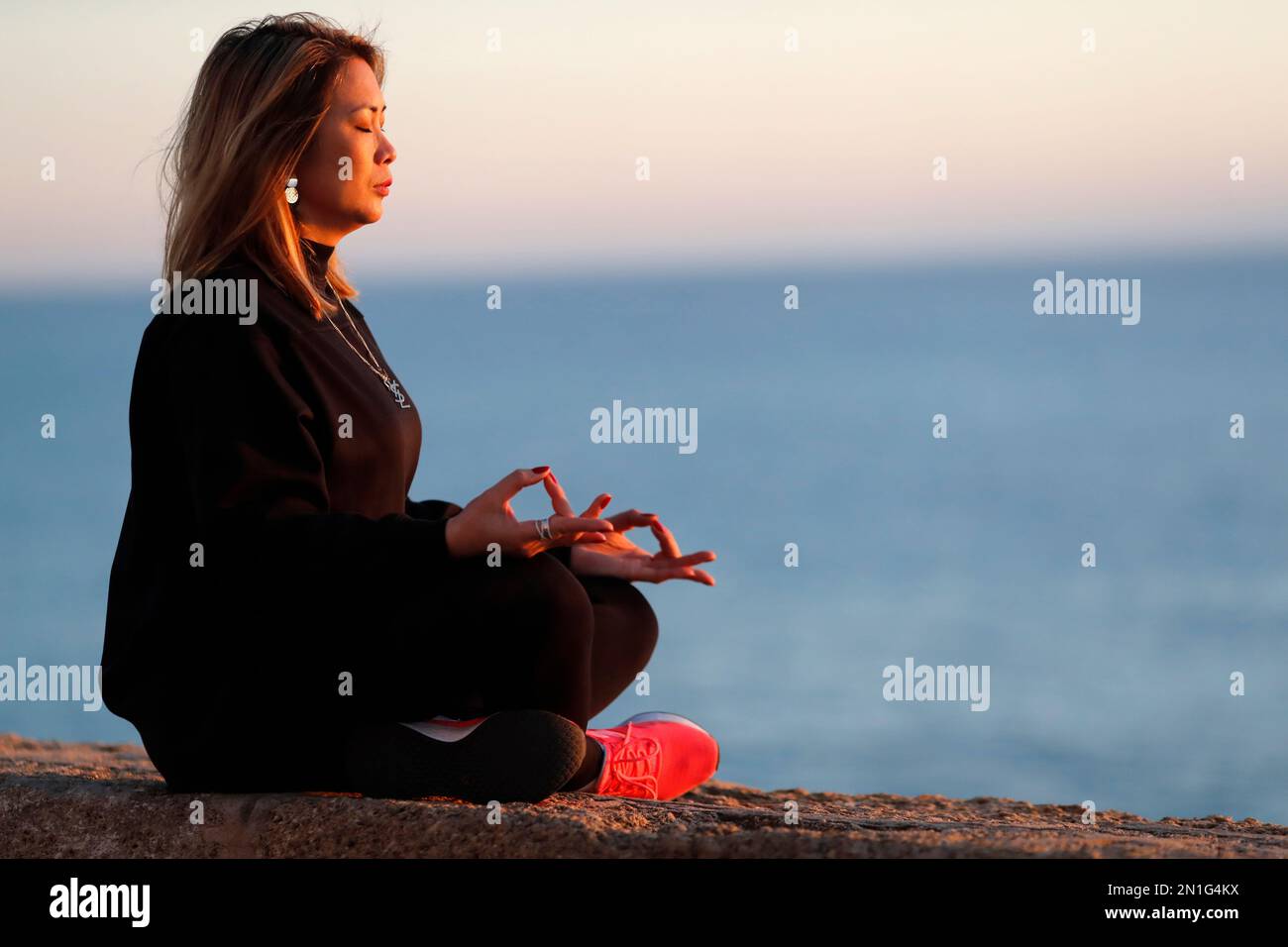 Donna che pratica yoga meditazione sul mare prima del tramonto come concetto di silenzio e relax, Spagna, Europa Foto Stock