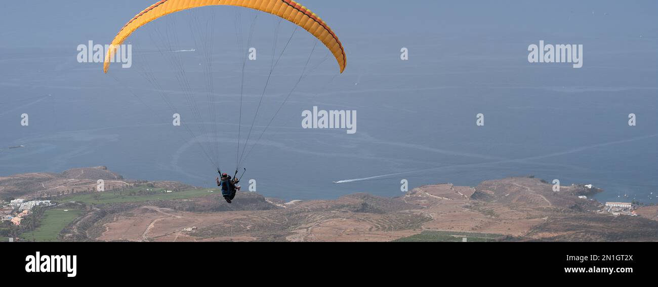 Parapendio tandem volare sopra l'oceano con l'acqua blu in una giornata di sole brillante Foto Stock