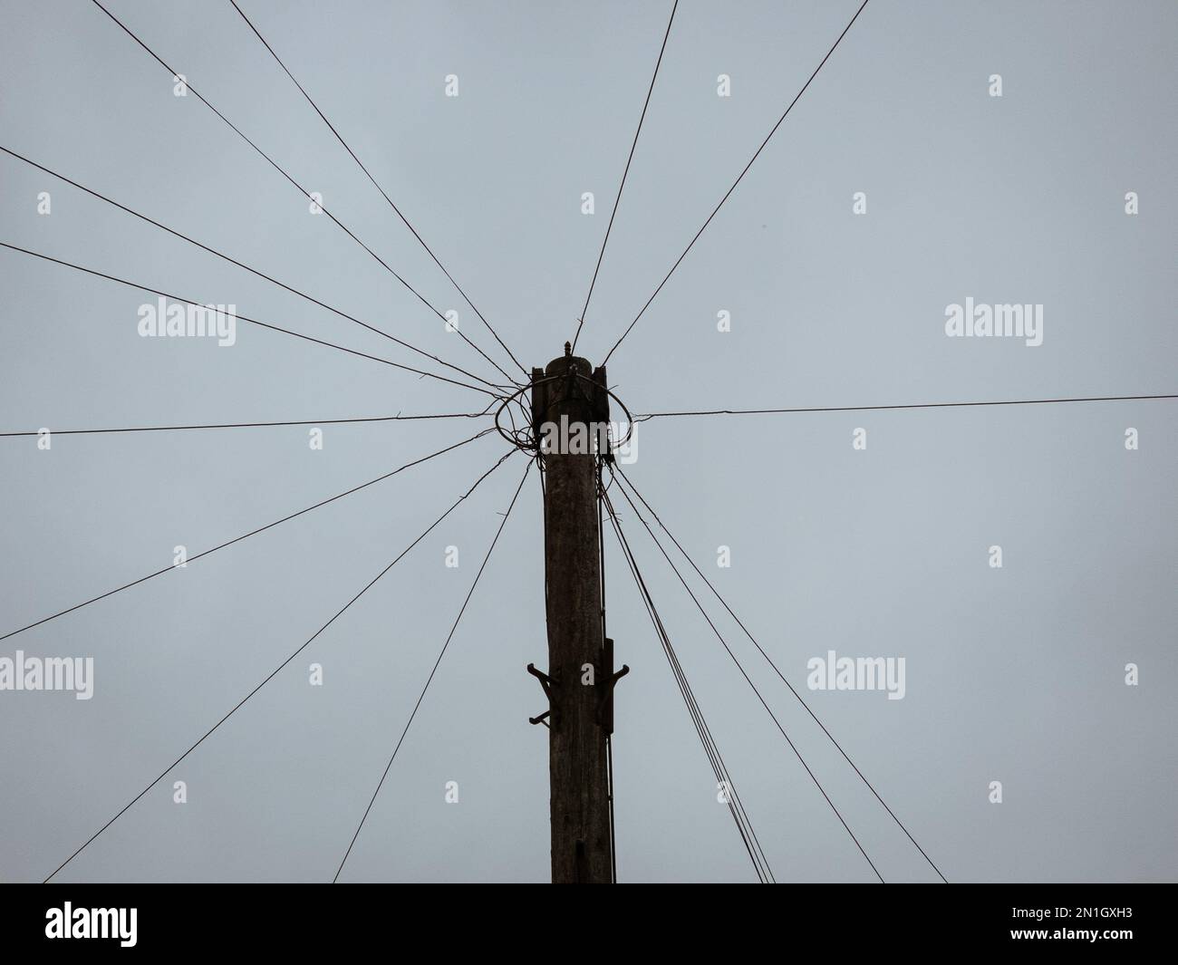 Un tiro a basso angolo di un palo per telecomunicazioni con fili in una giornata nuvolosa Foto Stock