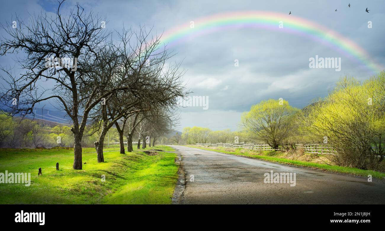 Arte paesaggio rurale ucraino. Paesaggio rurale primaverile con un arcobaleno su una strada rurale vuota con alberi primaverili Foto Stock