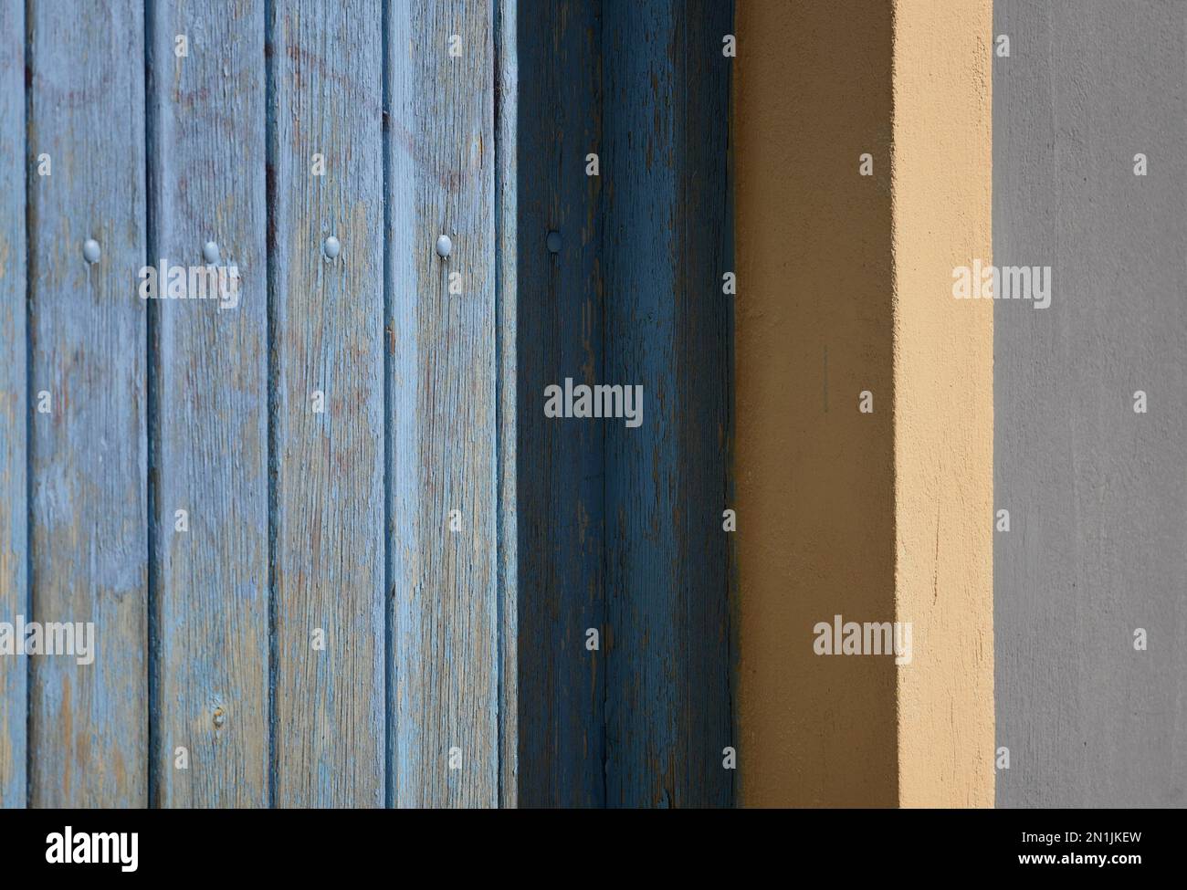 Vecchia casa rurale persiane in legno blu chiaro con finiture bianche su una parete di stucco veneziano. Foto Stock