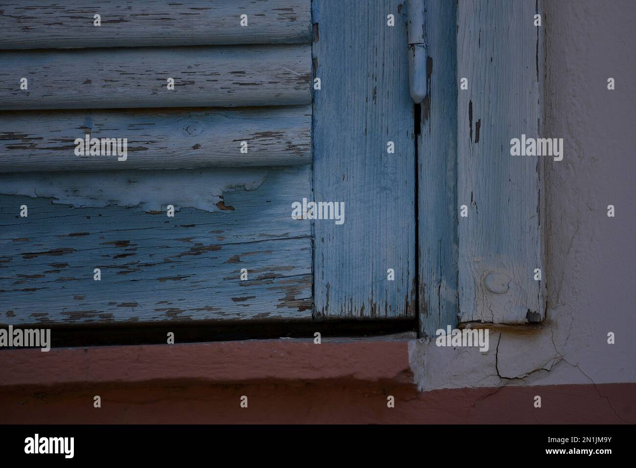 Vecchia casa rurale persiane in legno blu chiaro con finiture bianche su una parete di stucco veneziano. Foto Stock