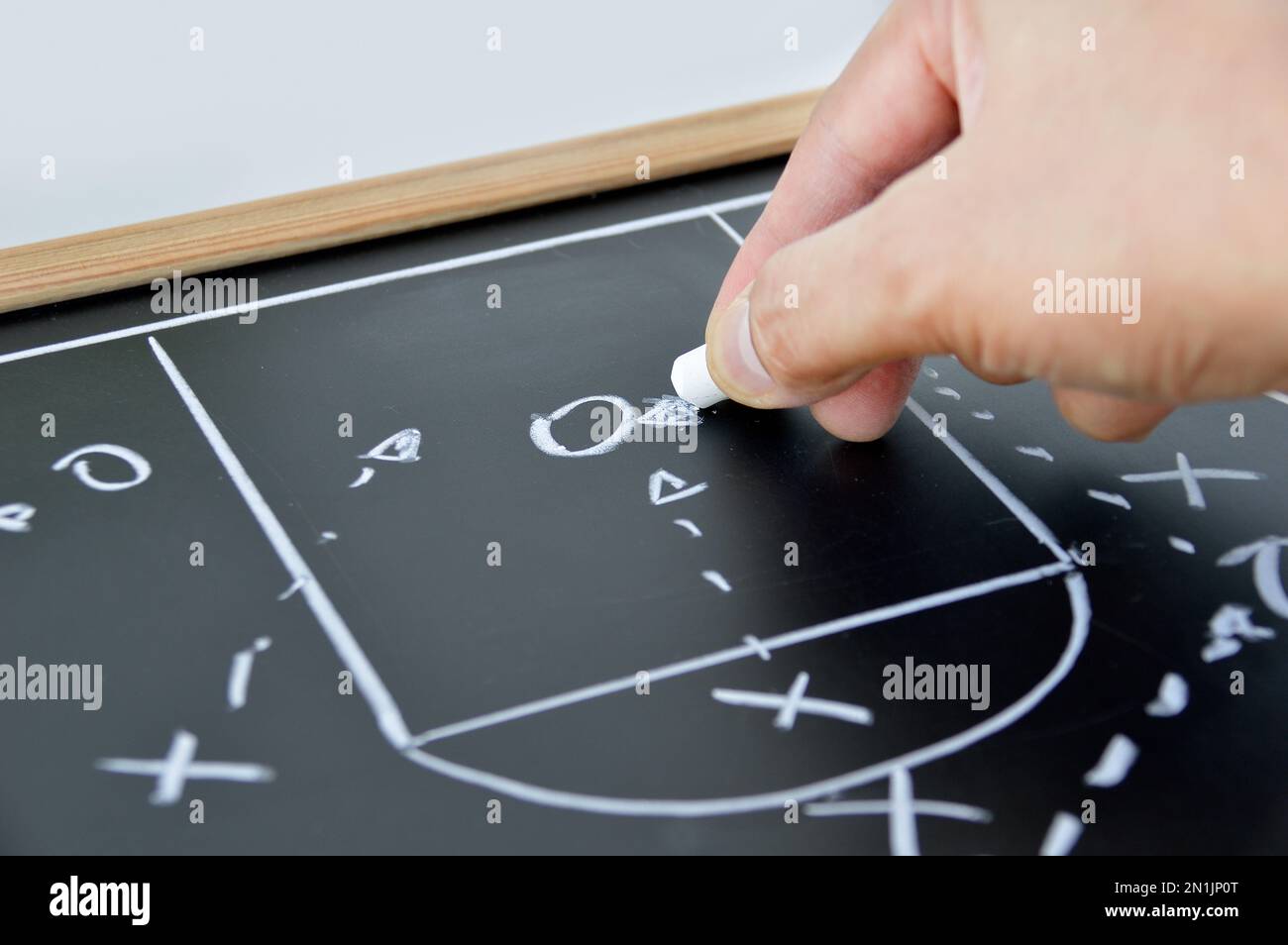 mano di un allenatore di basket che disegna una tattica di gioco con gesso bianco sulla lavagna Foto Stock