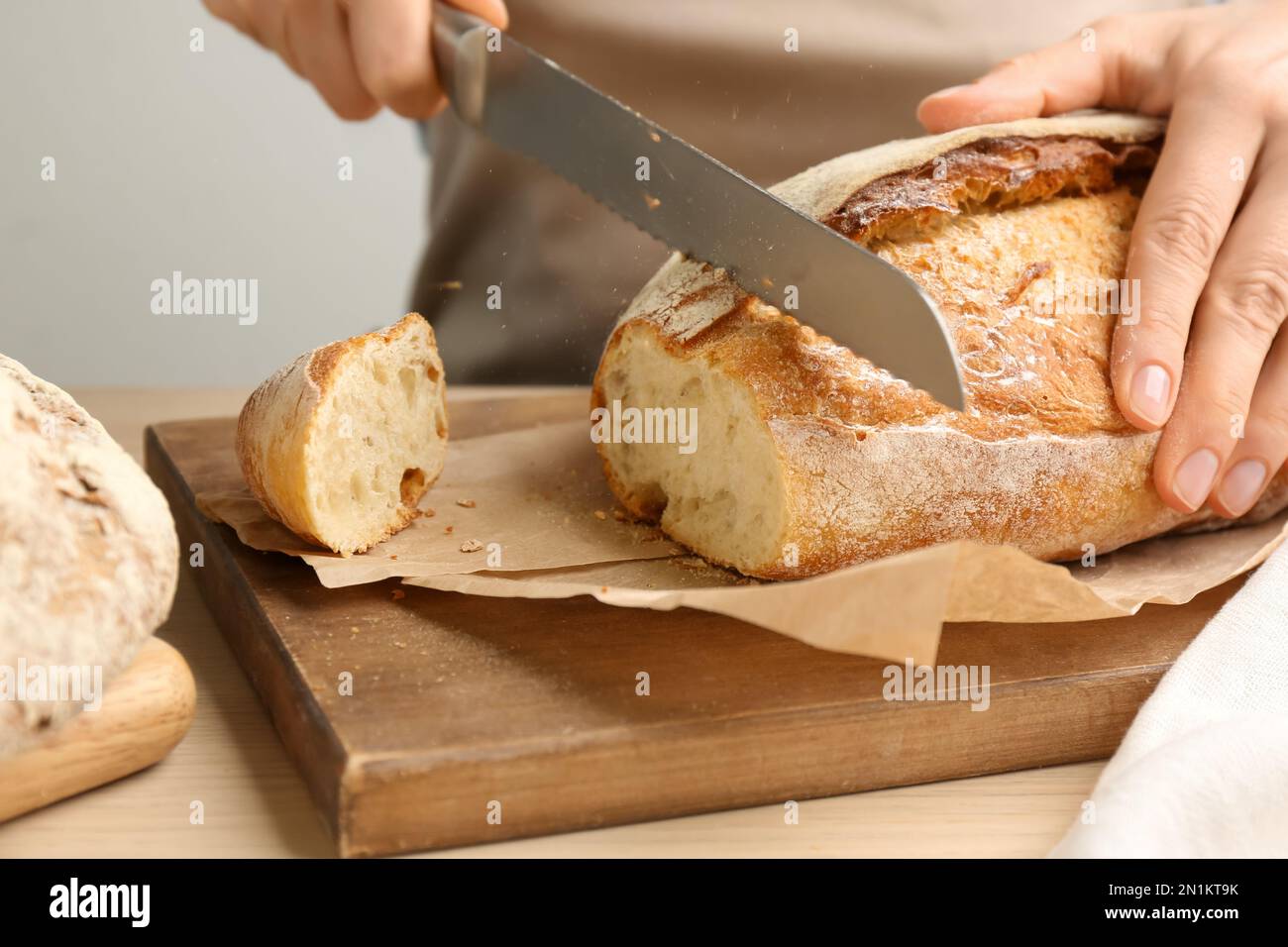 Donna che taglia pane appena sfornato a tavola di legno, primo