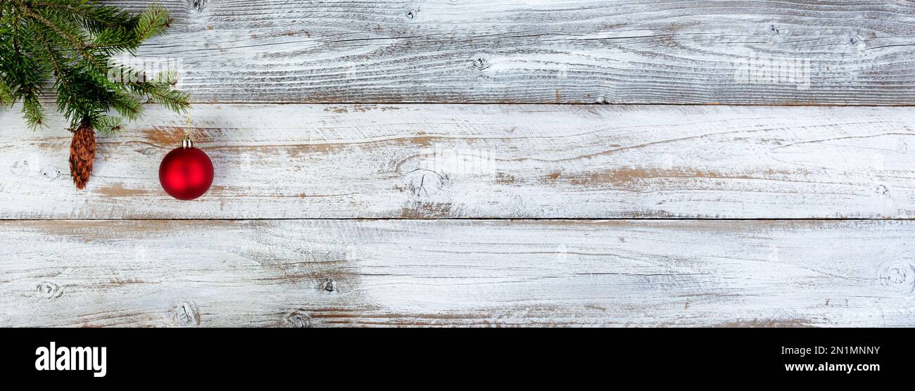 Decorazione natalizia con rametto in abete e ornamento a pallina rossa su fondo in legno bianco invecchiato Foto Stock